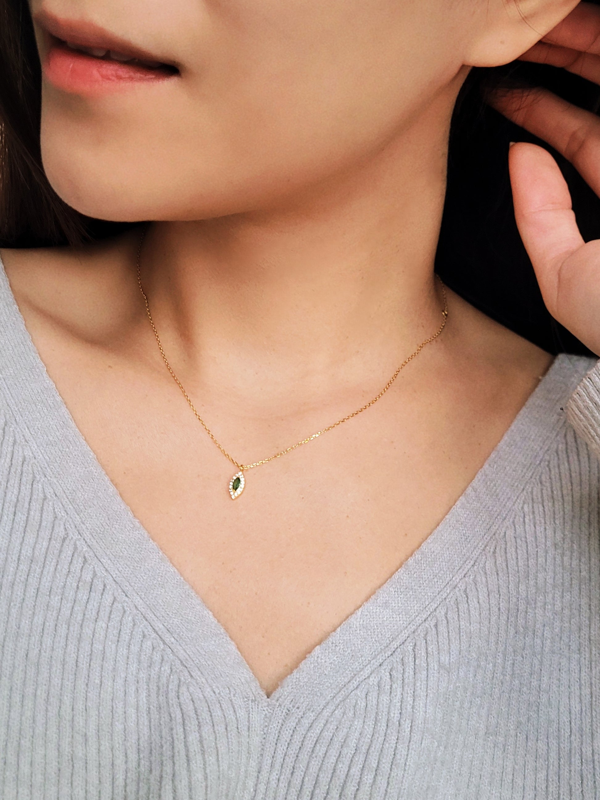 Close-up of a marquise emerald green evil eye pendant necklace on a delicate gold chain, showcasing its dainty and elegant vintage-inspired design.