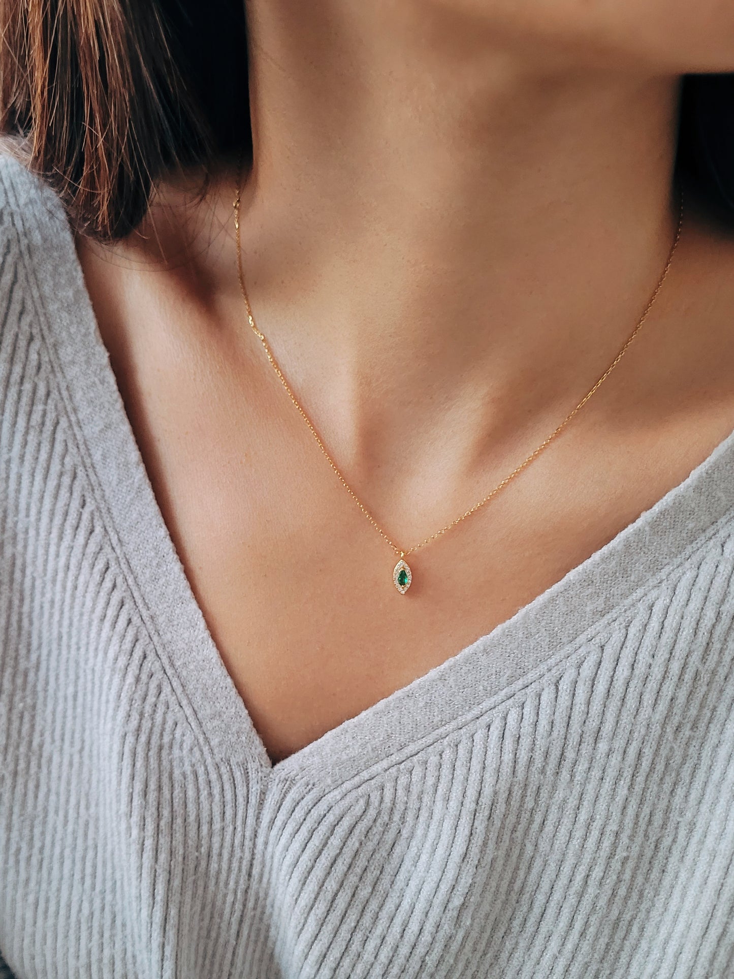 Close-up of a marquise emerald green evil eye pendant necklace on a delicate gold chain, showcasing its dainty and elegant vintage-inspired design.