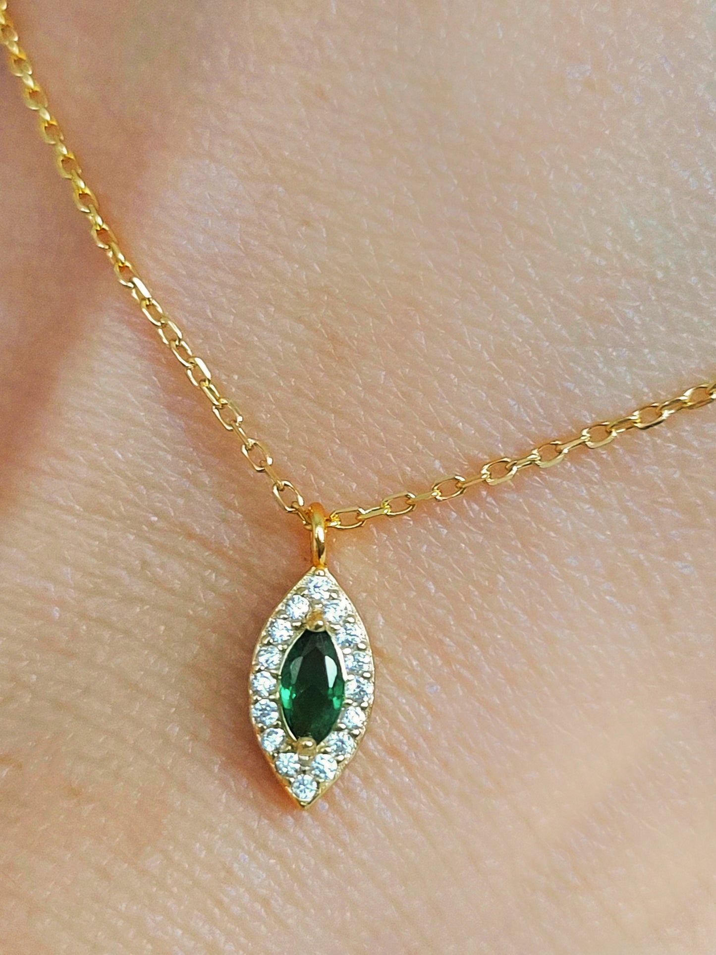 Close-up of a marquise emerald green evil eye pendant necklace on a delicate gold chain, showcasing its dainty and elegant vintage-inspired design.