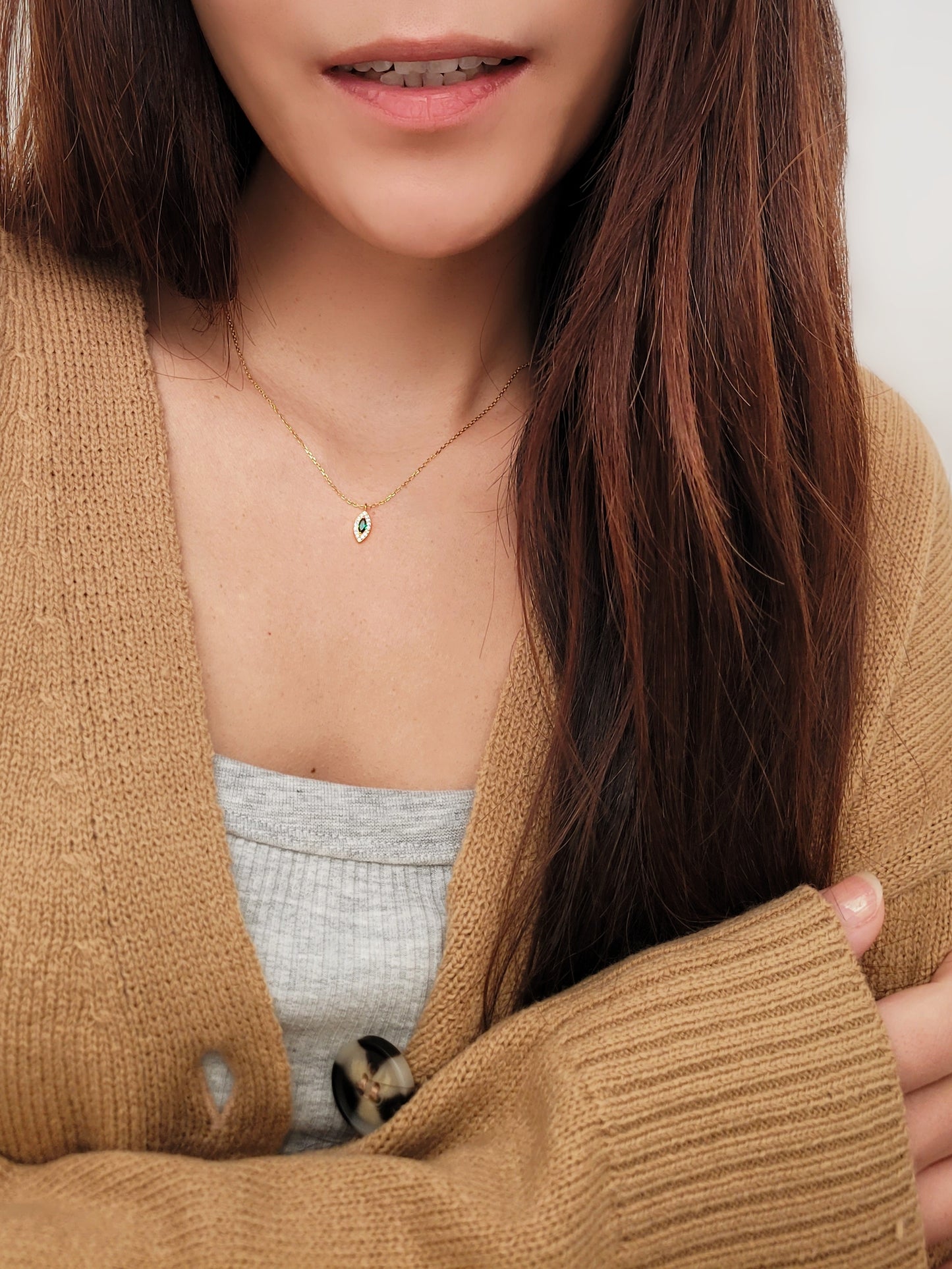 Close-up of a marquise emerald green evil eye pendant necklace on a delicate gold chain, showcasing its dainty and elegant vintage-inspired design.