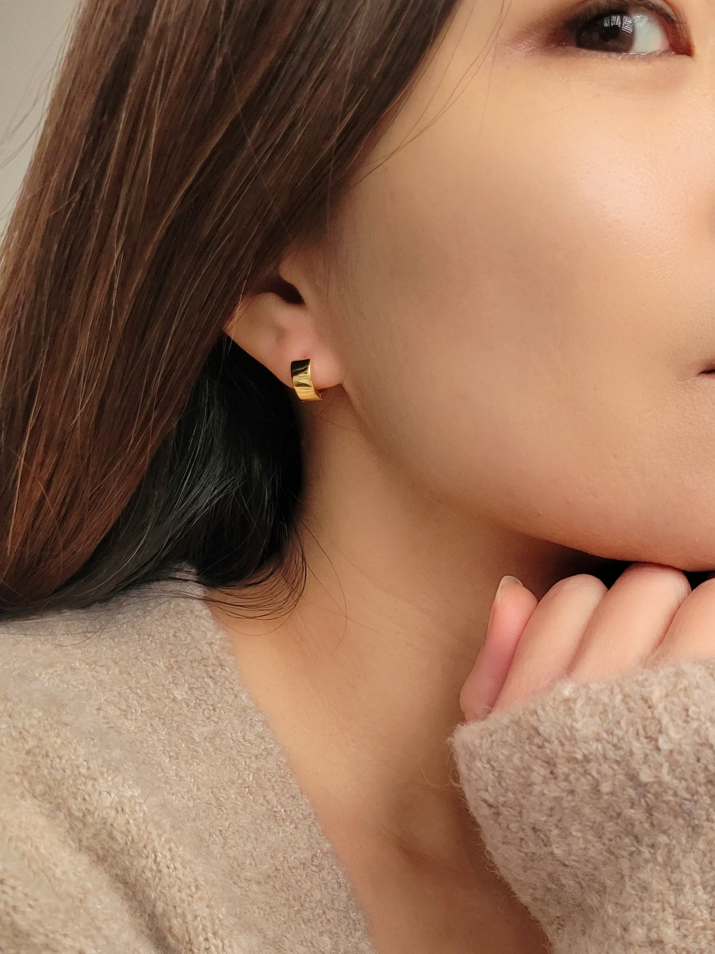 Minimalist chunky small gold huggie earrings worn by a woman, showcasing their stylish and versatile design perfect for everyday wear.