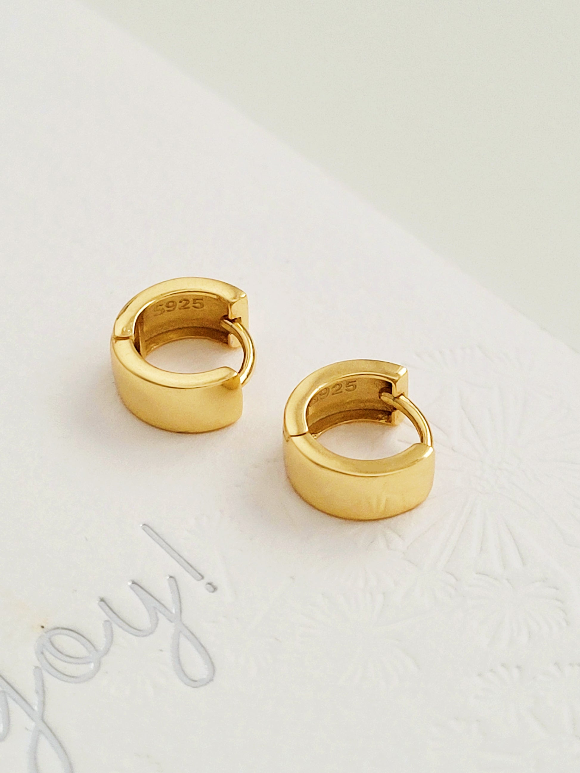 Stylish and minimalist chunky small gold hoop earrings displayed on a white surface showcasing their versatile design. Perfect gift for her.