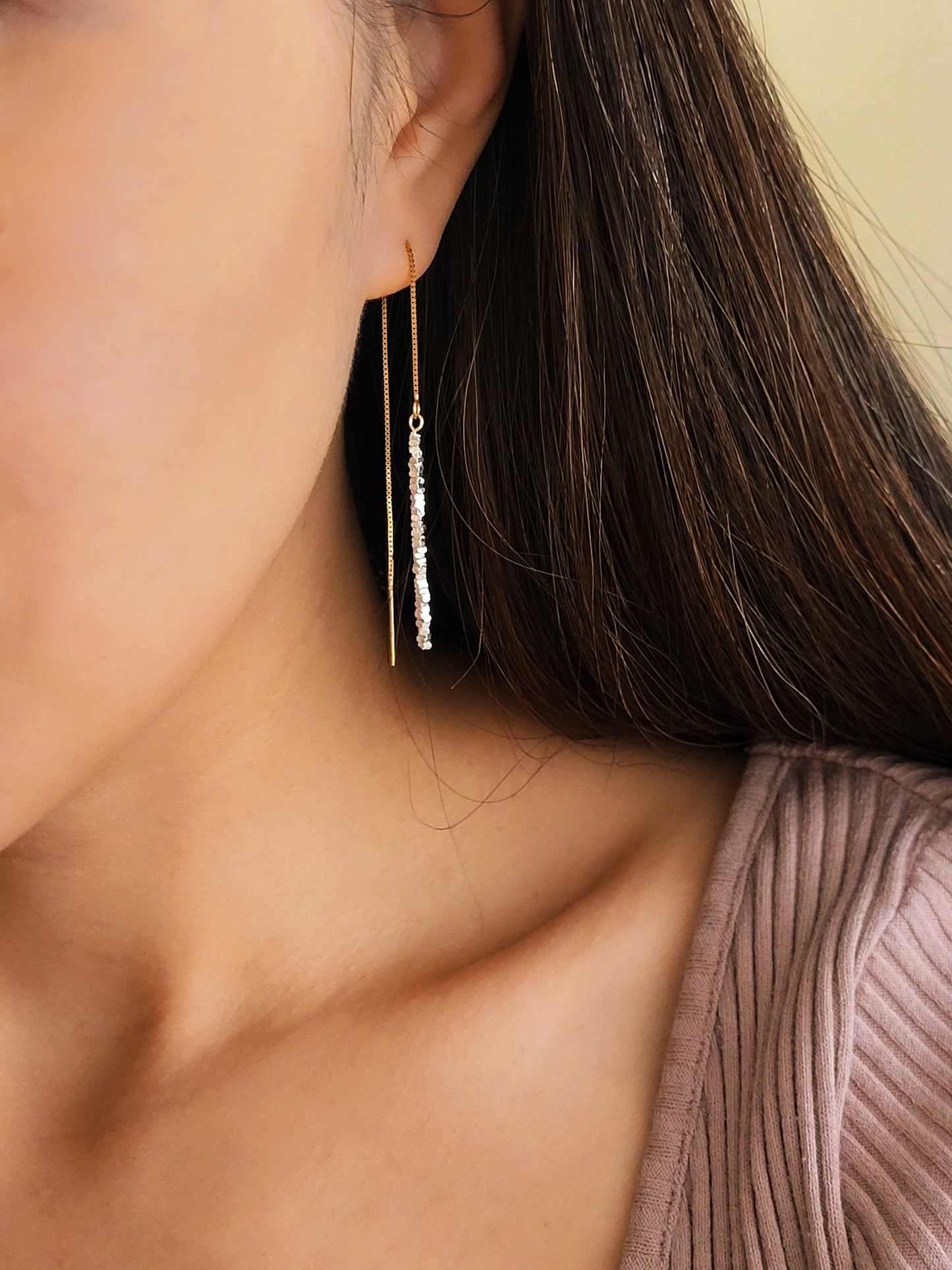 Woman wearing gold pull-through earrings with silver nuggets, showing the long drop length. A unique London jewellery gift.