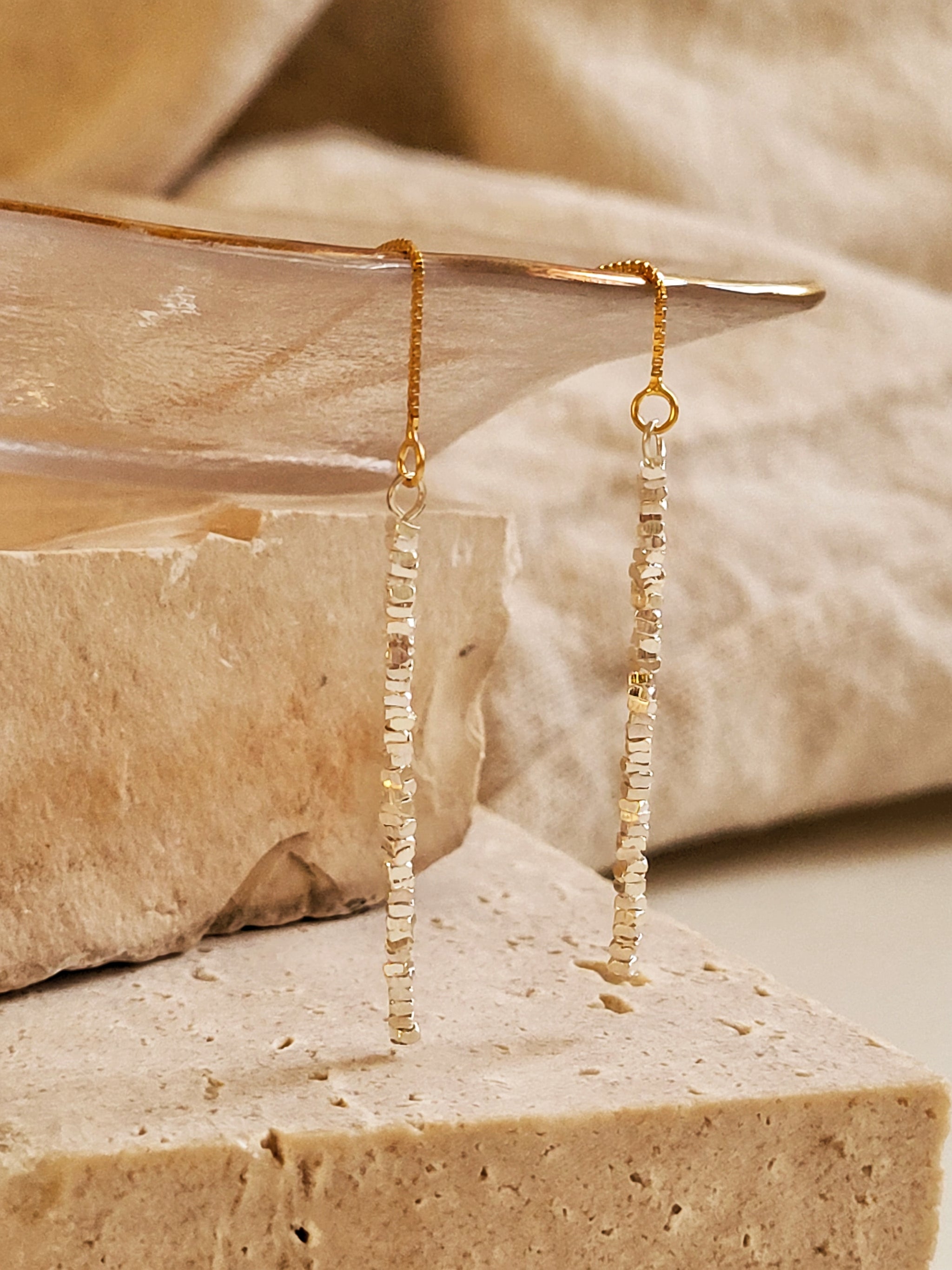 Detailed close-up of mixed metal threader earrings with sterling silver nuggets texture bar on a gold-plated ear wire.
