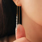 Woman wearing gold pull-through earrings with silver nuggets, showing the long drop length. A unique London jewellery gift.