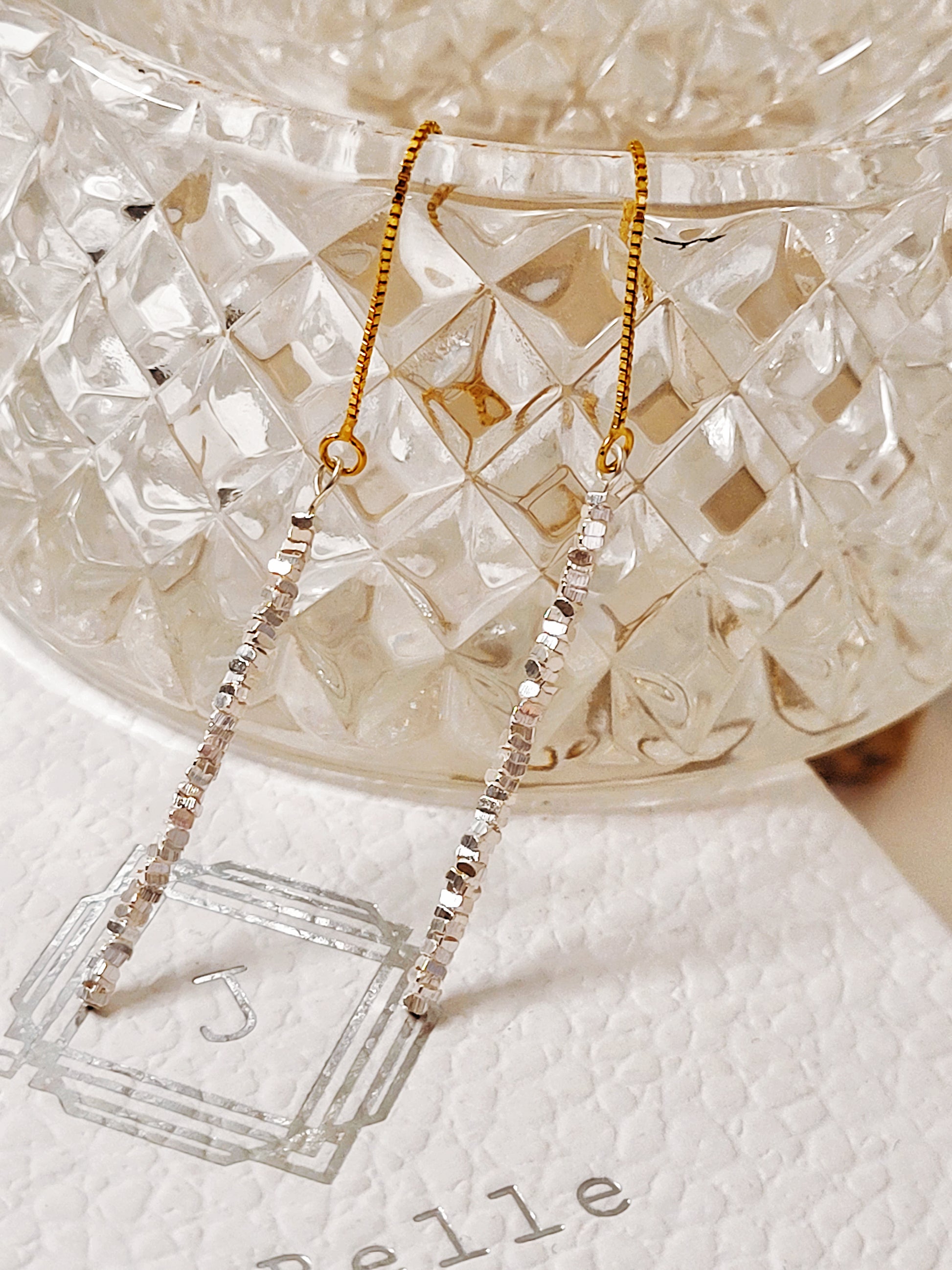 Close-up of shimmering sterling silver nuggets with a raw organic texture on a gold-plated ear wire.