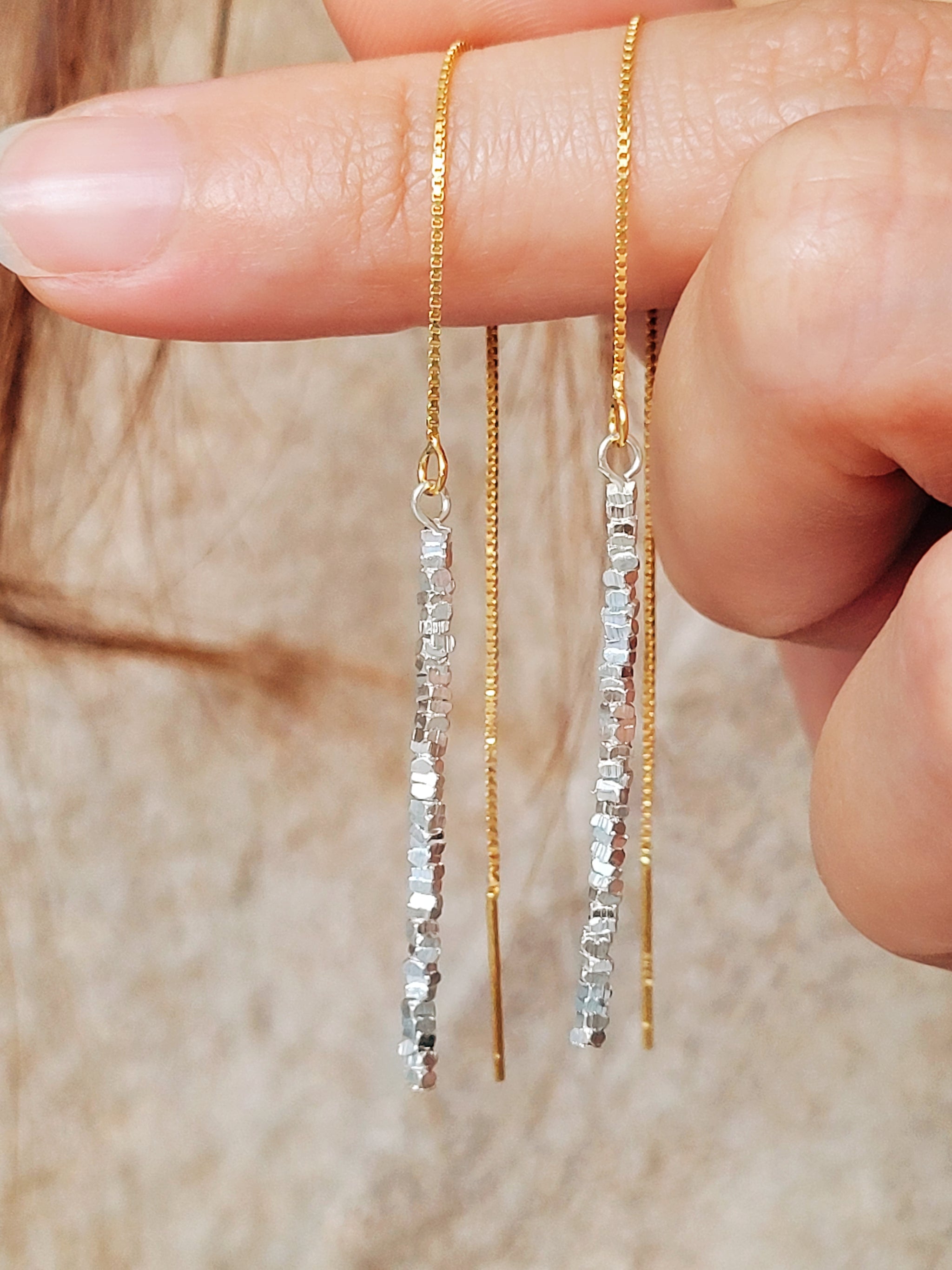 Detailed close-up of shimmering sterling silver nuggets with a raw organic texture on a gold-plated ear wire.