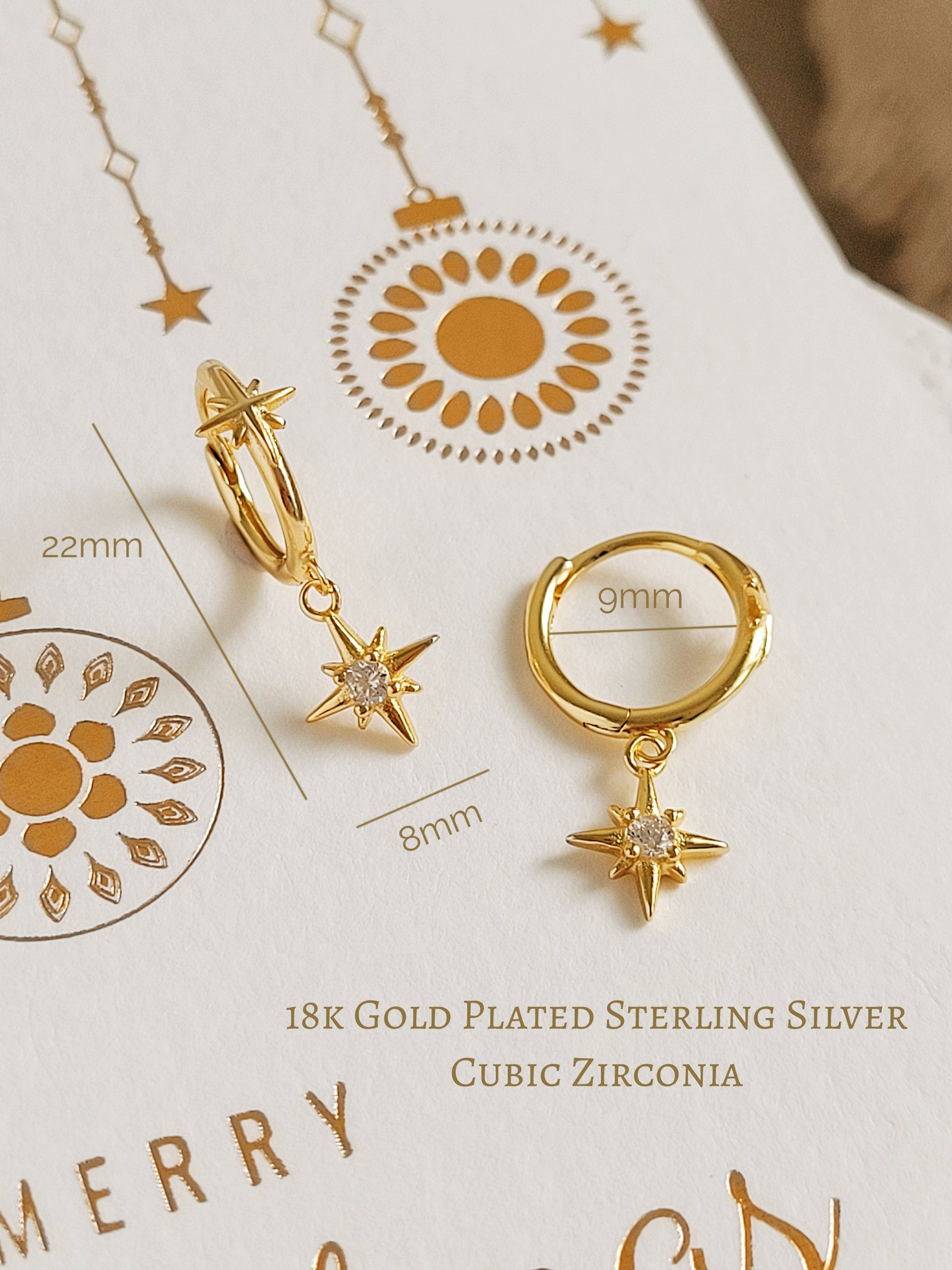 Gold hoop earrings with northern star charms on a Christmas card