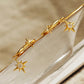 Gold star earrings with dangly north star charms on a neutral background