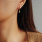 Close-up of a person wearing a gold earring with a star design.