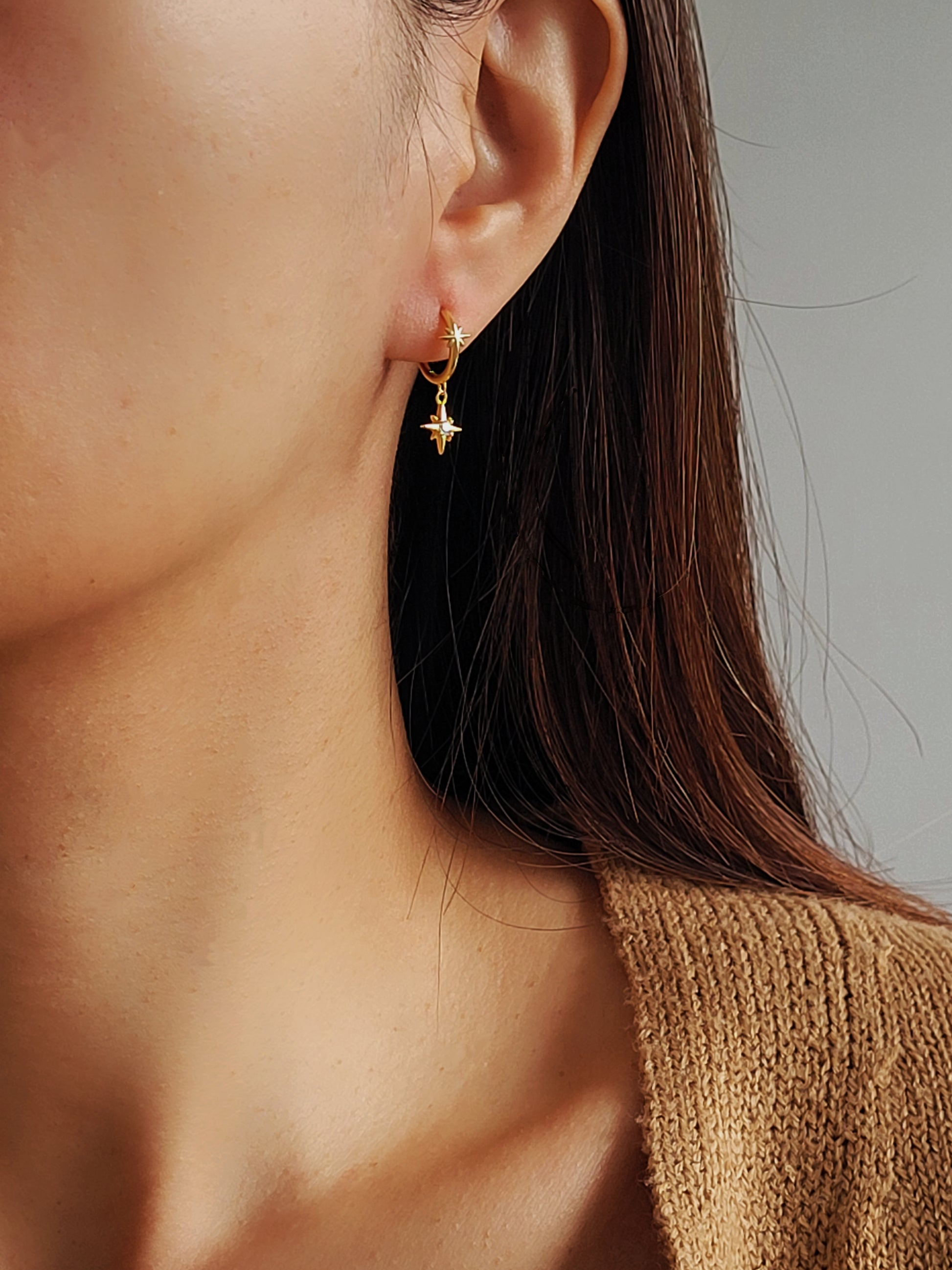 Close-up of a person wearing a gold earring with a star design.