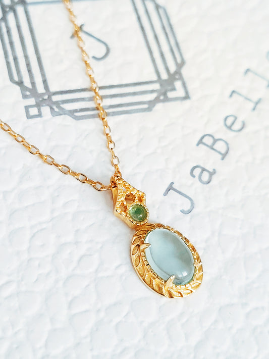 Close-up of pale blue topaz oval pendant necklace with vintage gold detailing. Perfect birthday gift for her.