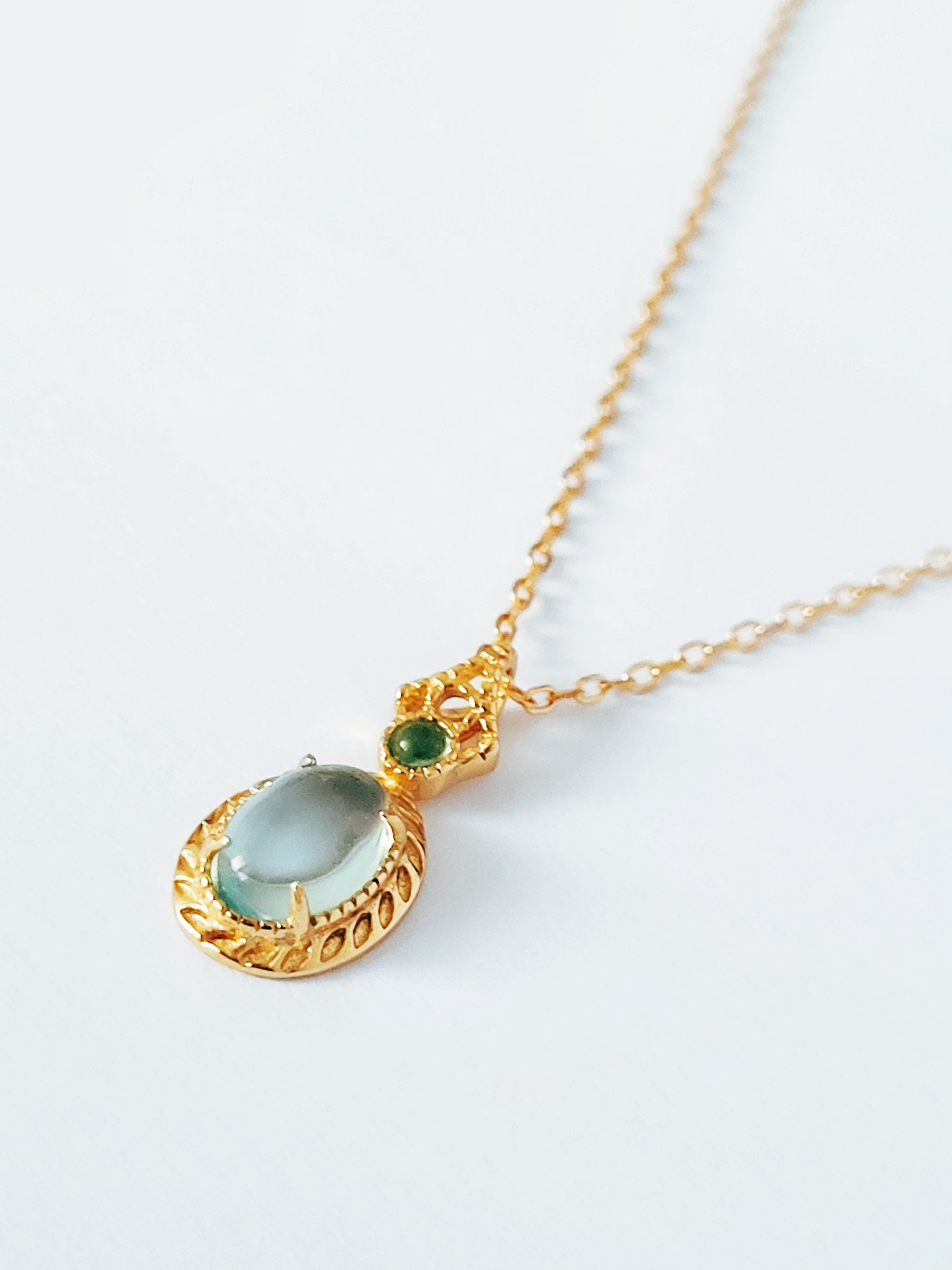 Close-up of pale blue topaz oval pendant necklace with vintage gold detailing. Perfect anniversary gift for her.