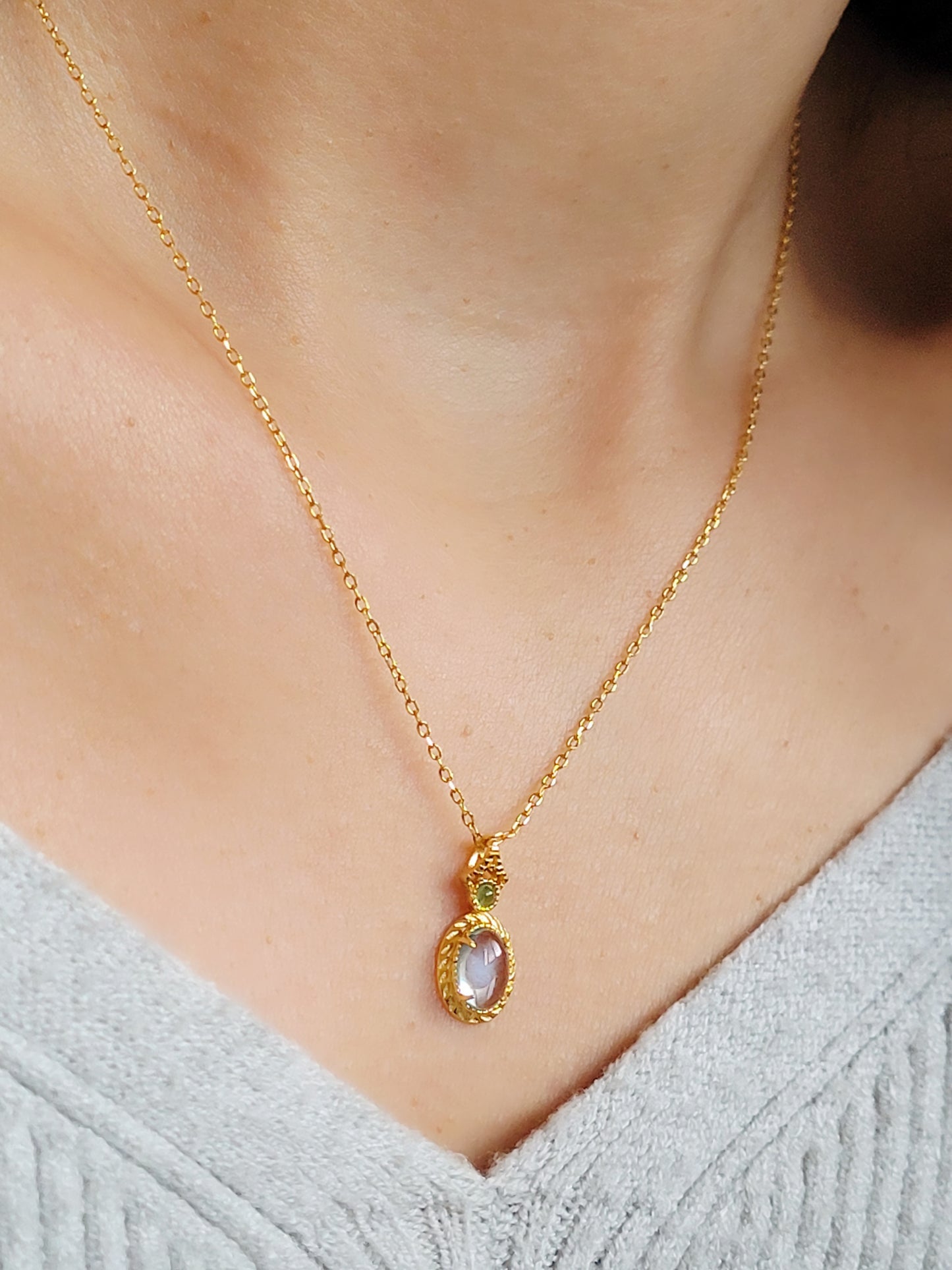 A woman wearing a dainty vintage inspired topaz and gold necklace with a green cubic zirconia.  Perfect anniversary gift for her.