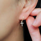 A gold cross earring worn on an ear, showcasing its dainty design and elegant fit, perfect for everyday or special occasions
