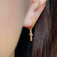 A gold cross earring worn on an ear, showcasing its dainty design and elegant fit, perfect for everyday or special occasions