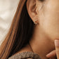Side view of a woman wearing a sparkling flower huggie earrings featuring shimmering cz stone, minimalist and stylish