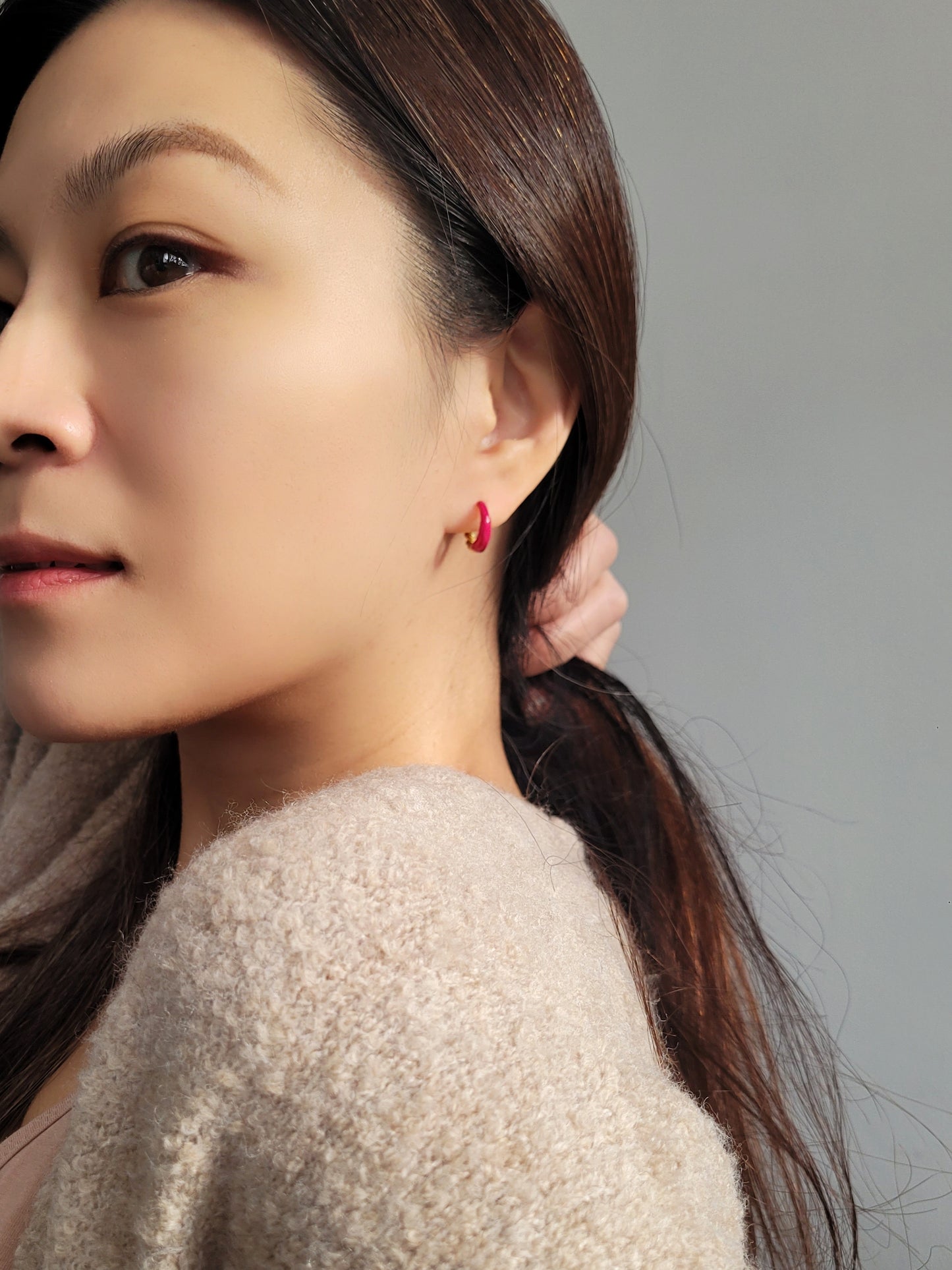 Close-up view of pink and gold enamel hoop earrings featuring twisted gold detail and vibrant green enamel finish.