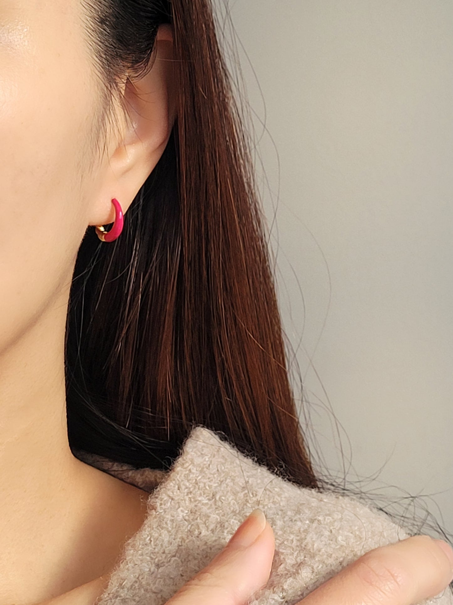 Close-up view of pink and gold enamel hoop earrings featuring twisted gold detail and vibrant green enamel finish.