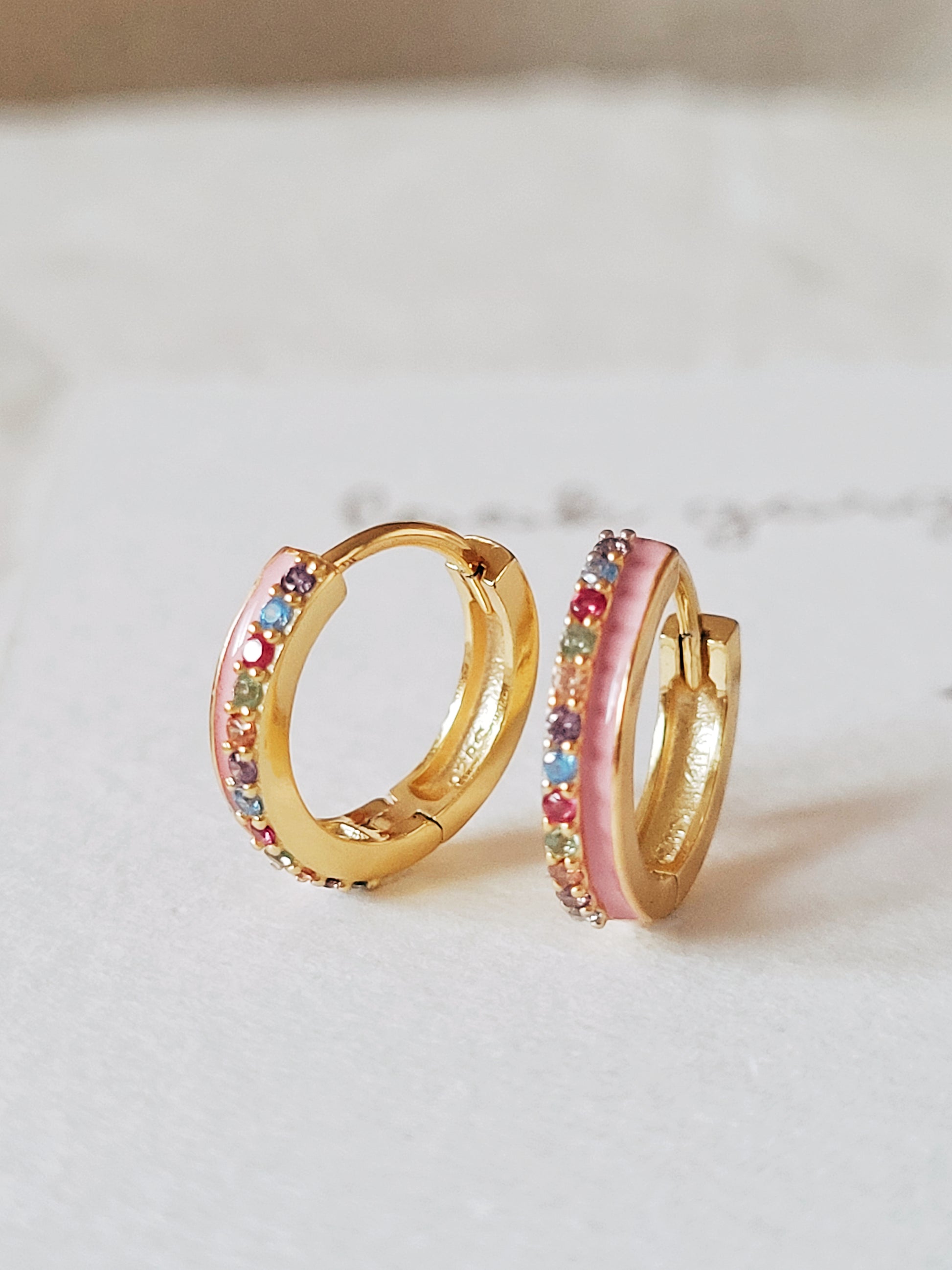 Funky pink enamel hoop earrings with rainbow crystal styled for a boho chic look. Crafted in gold plated sterling silver.