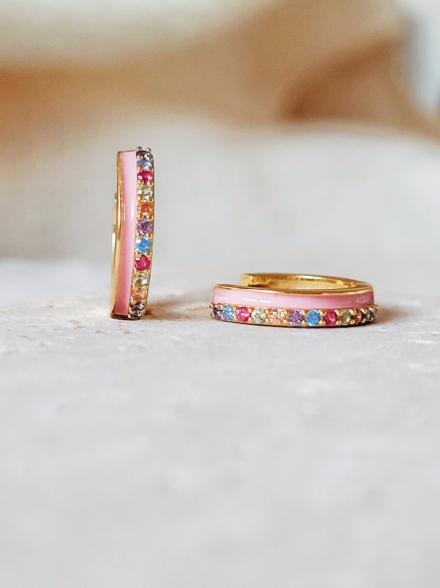 Statement pink enamel huggie earrings adorned with rainbow colored cubic zirconia on gold plated sterling silver.