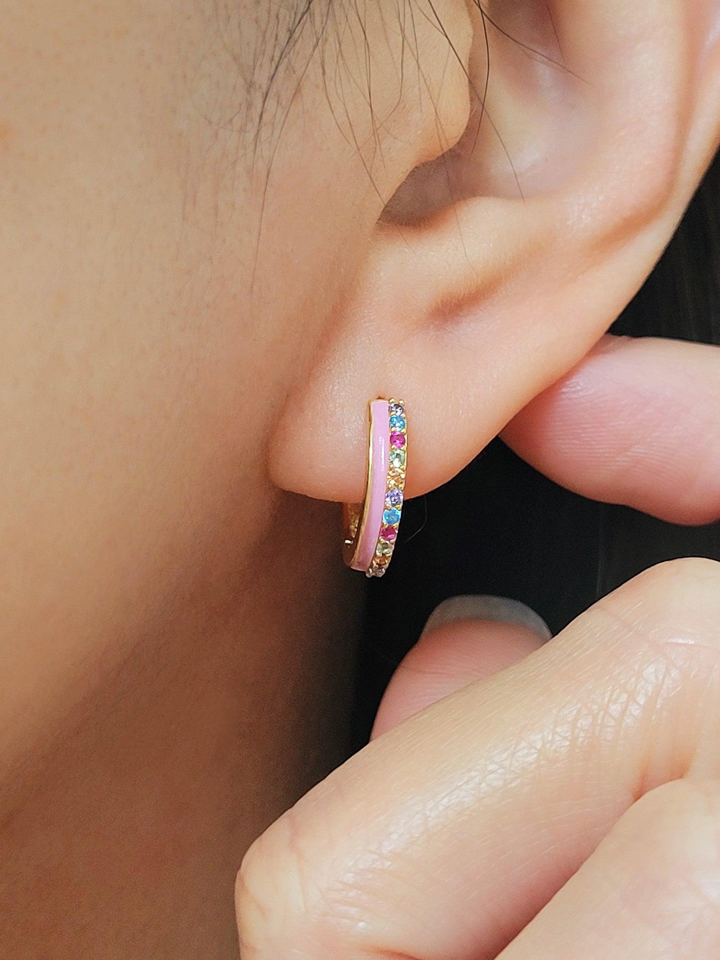 Close up of a woman wearing statement pink enamel hoop earrings with rainbow crystal styled for a boho chic look. Crafted in gold plated sterling silver.