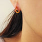 Model wearing pink enamel rainbow huggie hoop earrings with gold finish and multicolor CZ stones, showing small hoop size and elegant fit on ear.