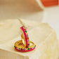 Pair of pink enamel huggie hoop earrings with multicolor cubic zirconia gemstones set in 18k gold plated sterling silver, displayed on a stone background.
