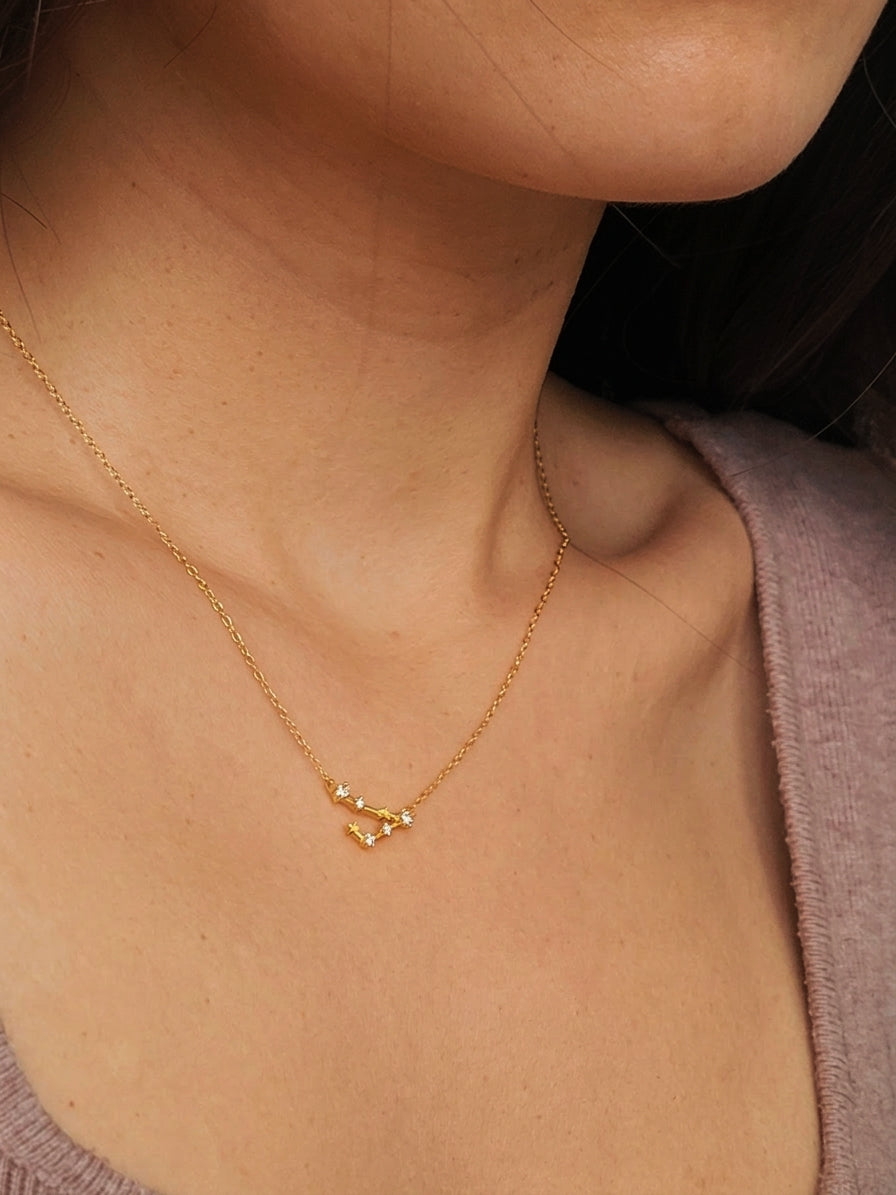 Close-up of a woman wearing an Pisces necklace showcasing the luxury aesthetic and pendant scale. Crafted in gold vermeil, a perfect jewellery gift for her.
