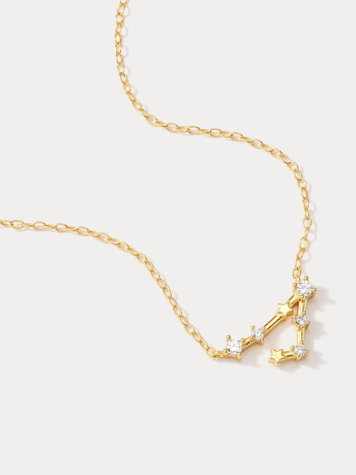 A dainty gold necklace with a pendant featuring a stylized Pisces zodiac constellation sign with sparkling zircons, thoughtful jewellery gift for her.