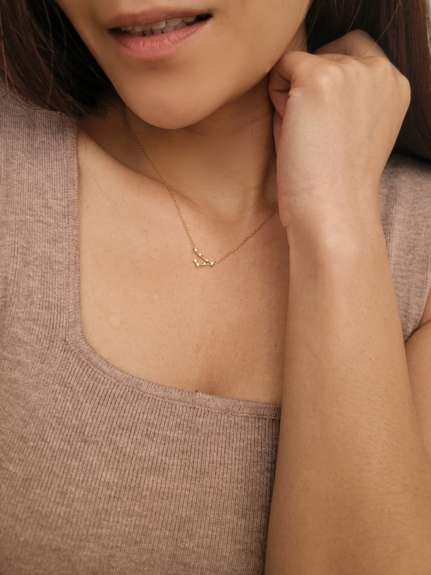Close-up of a woman wearing an Pisces necklace showcasing the luxury aesthetic and pendant scale. Crafted in gold vermeil, a perfect jewellery gift for her.
