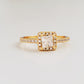 A stunning gold ring featuring a radiant princess square-cut diamond at its center, surrounded by a halo of sparkling smaller diamonds, showing its opulence and intricate craftsmanship.