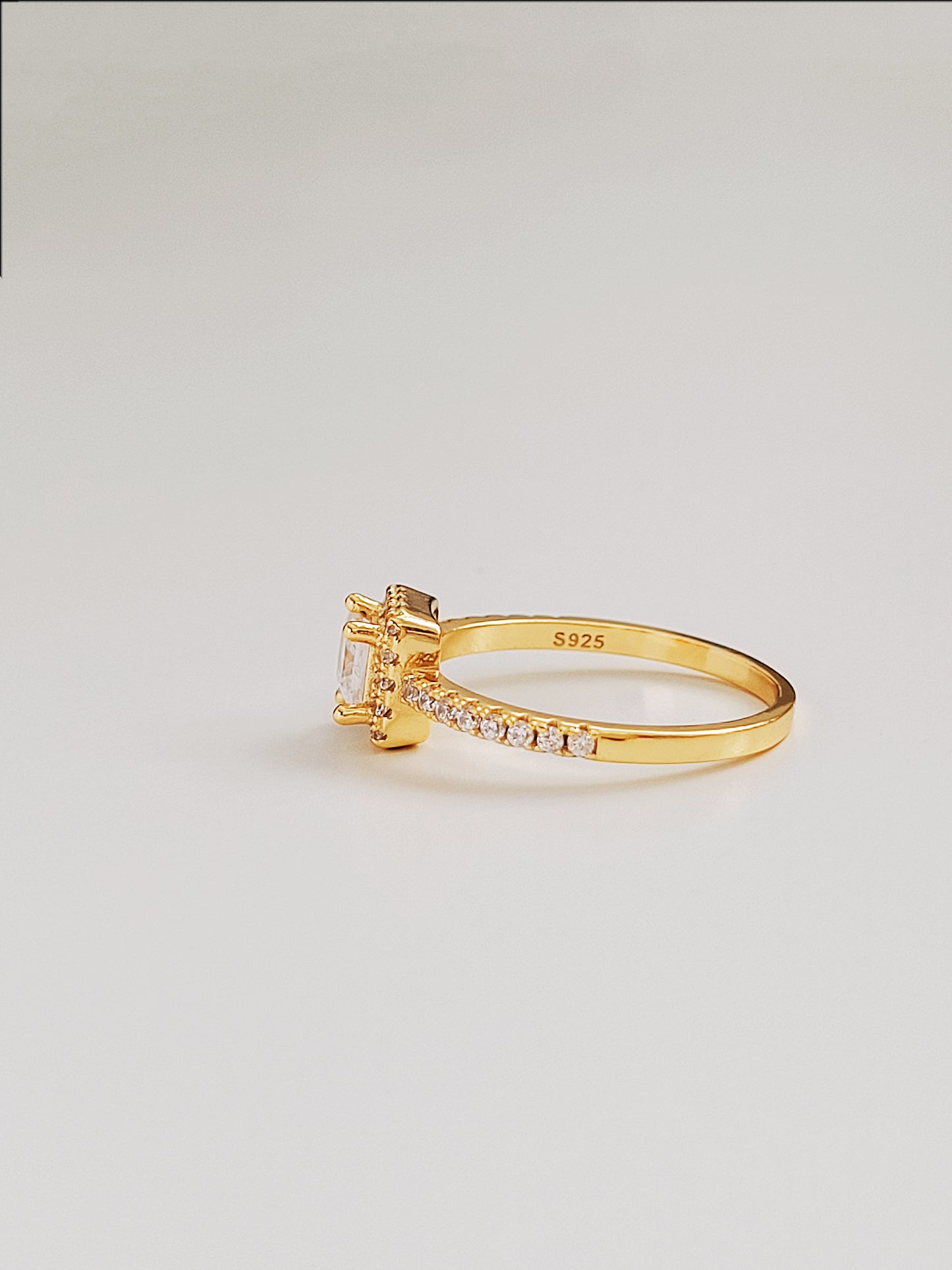 A stunning yellow gold ring with a princess cut solitaire diamond at center, embellished with diamonds along the sides for added brilliance.