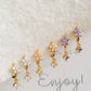 Close-up of a pair of dainty purple flower huggie earrings with dangling charm in 18k gold plated sterling silver and cubic zirconia.