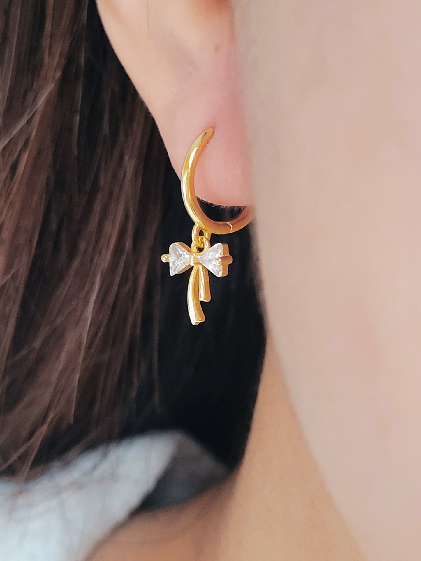 Close-up view of a woman&#39;s ear wearing ribbon bow earring with a dangling design, perfect for gifting to girlfriends, daughters, or loved ones.