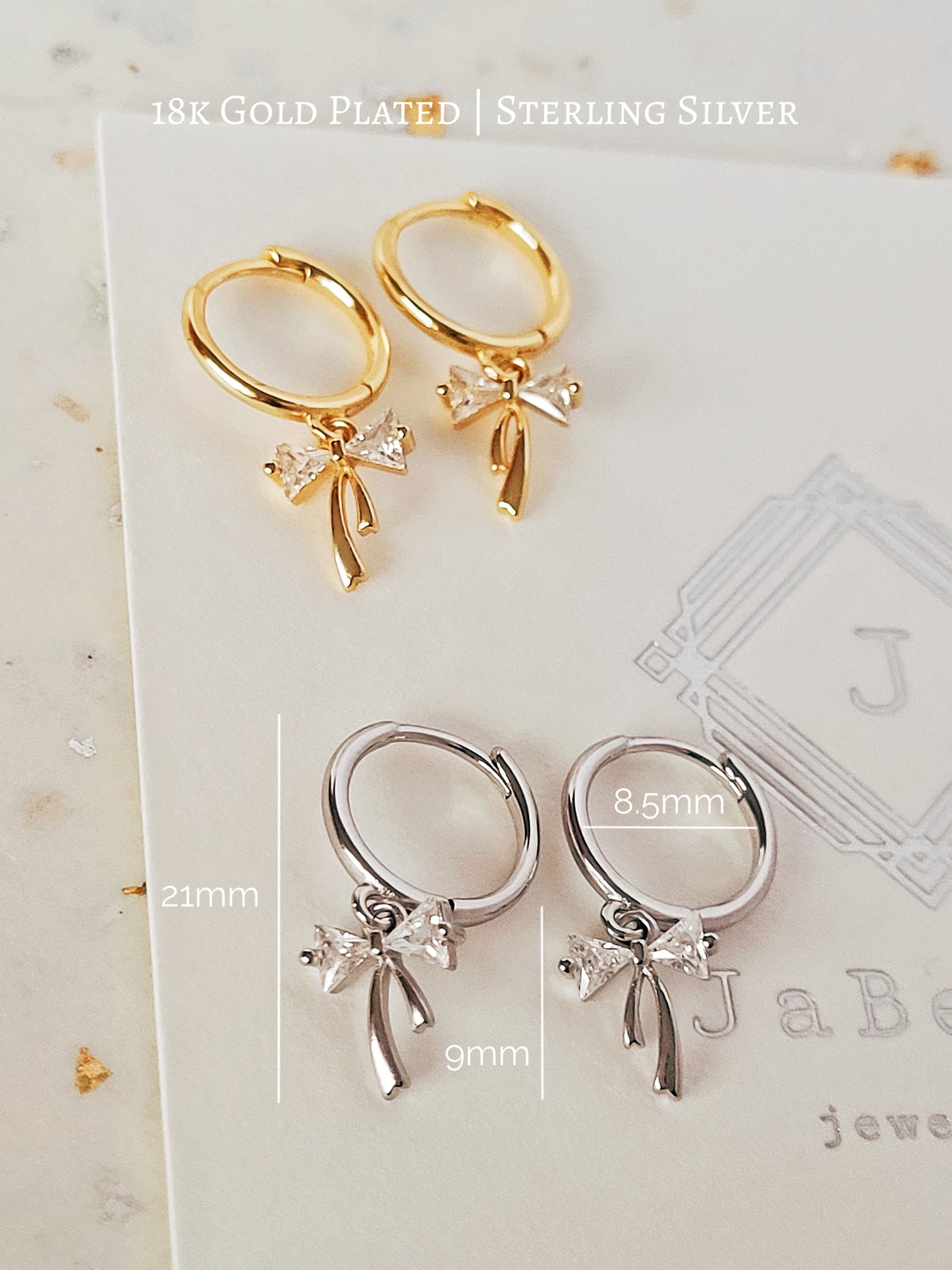 2 Pairs of Gold-plated and sterling silver ribbon bow dangly huggie earrings displayed on a neutral stone background.