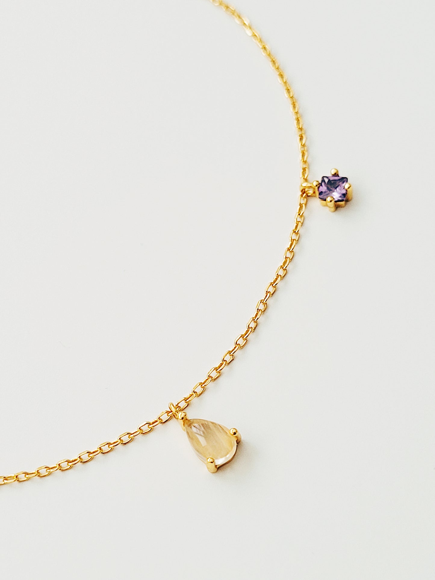 Opulent gold plated bracelet showcasing a rich purple amethyst charm and golden rutilated quartz.