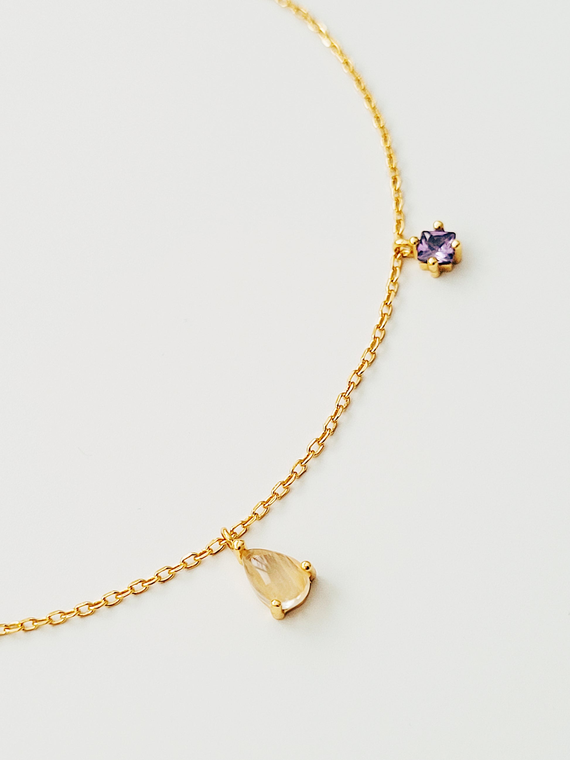 Opulent gold plated bracelet showcasing a rich purple amethyst charm and golden rutilated quartz.