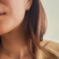 model wearing blue star huggie earrings in gold, stylish and minimalist style.