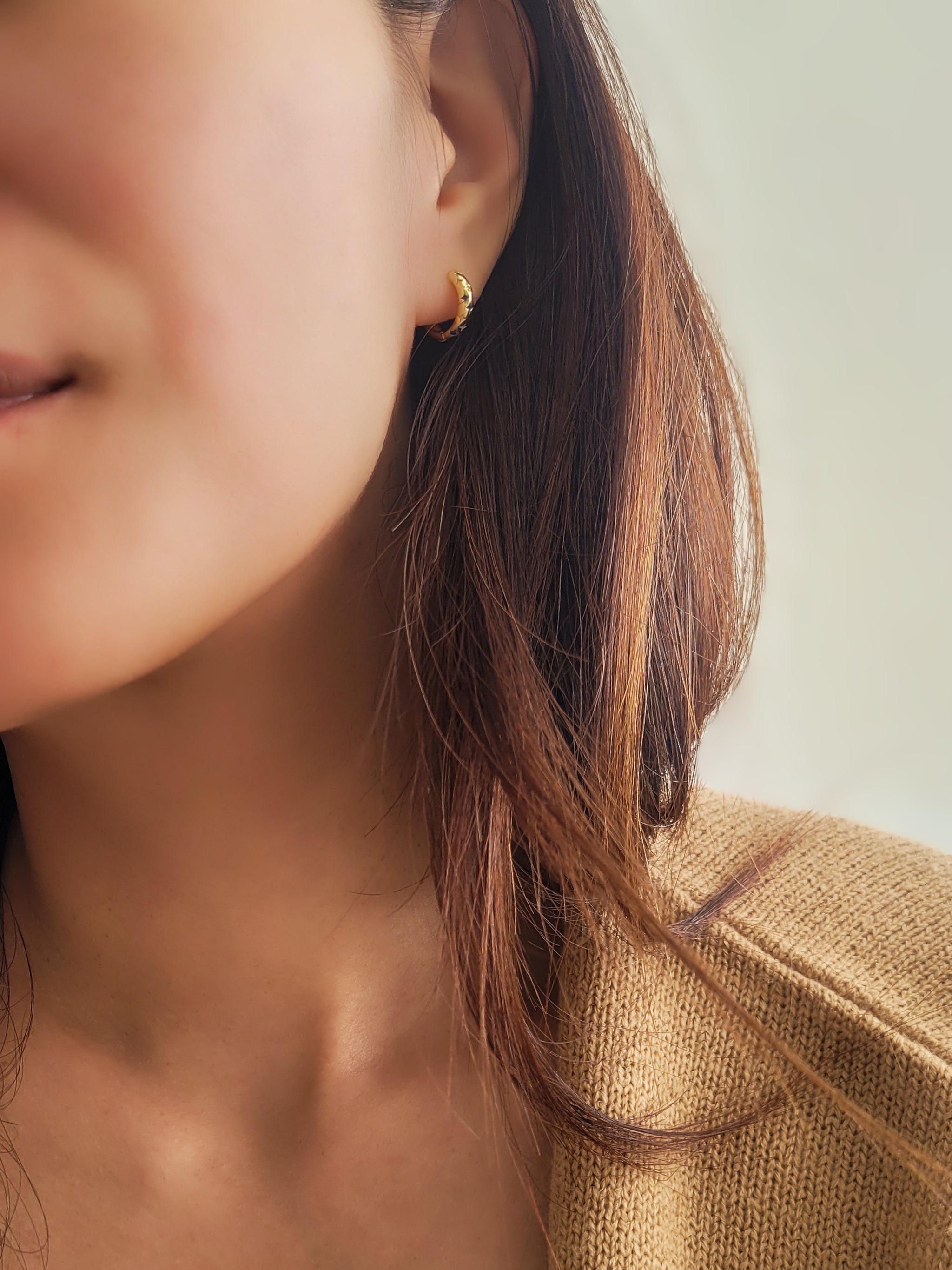 model wearing blue star huggie earrings in gold, stylish and minimalist style.