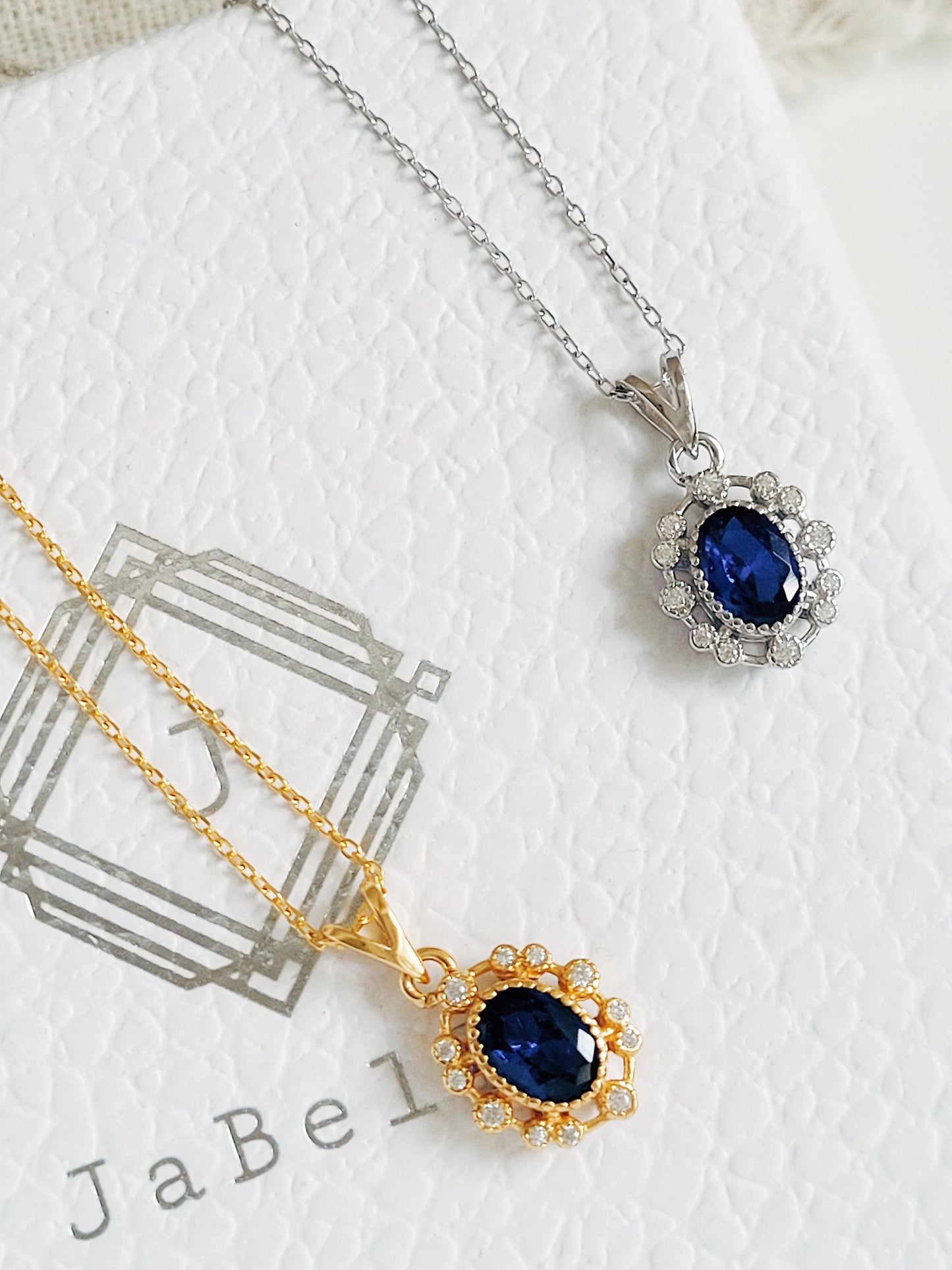 Two necklaces with blue gemstones on a white background, crafted in gold plated sterling silver.