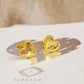 Gold heart stud earrings with scalloped texture on a white surface with a beige background