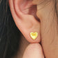 Close up of a woman wearing 18k gold plated heart stud earrings with sparkling texture