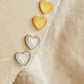 Pairs of gold heart studs and silver heart studs displayed on a beige paper with dimensions.