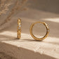 Pair of 18k gold plated sterling silver star huggie hoop earrings with cubic zirconia stones displayed on a textured stone surface.