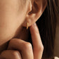 Close-up of a person wearing a gold hoop earring, perfect for everyday wear