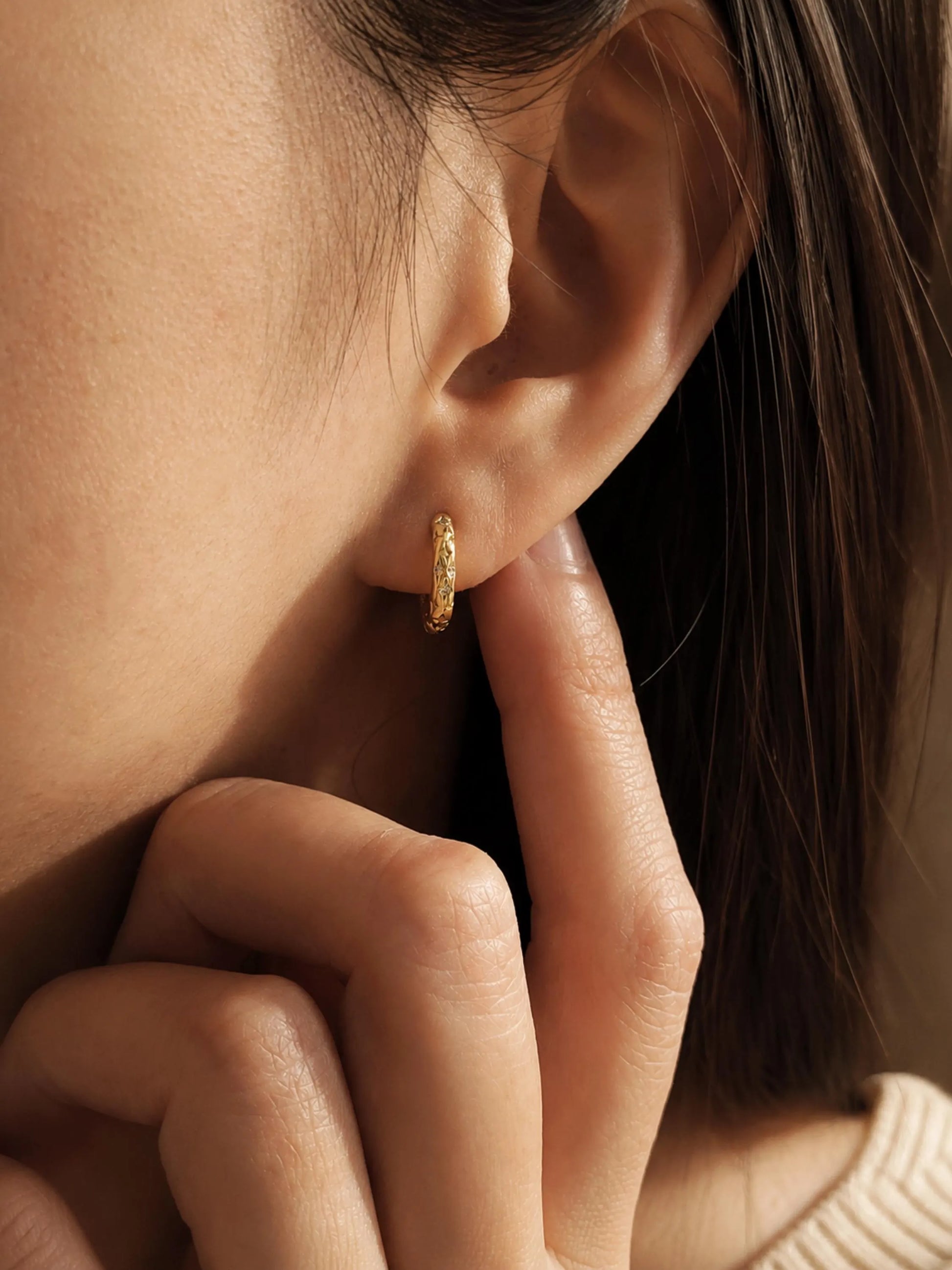 Close-up of a person wearing a gold hoop earring, perfect for everyday wear