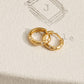 Pair of 18k gold-plated star huggie hoop earrings with cubic zirconia set on a textured beige jewelry box featuring an JaBelle logo.
