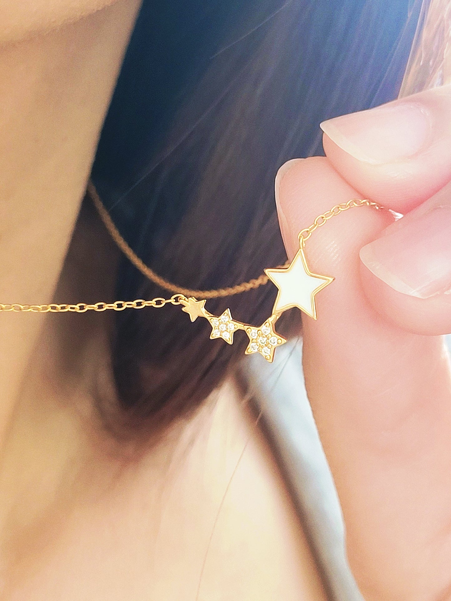 Close-up of a woman's hand holding Star Necklace.