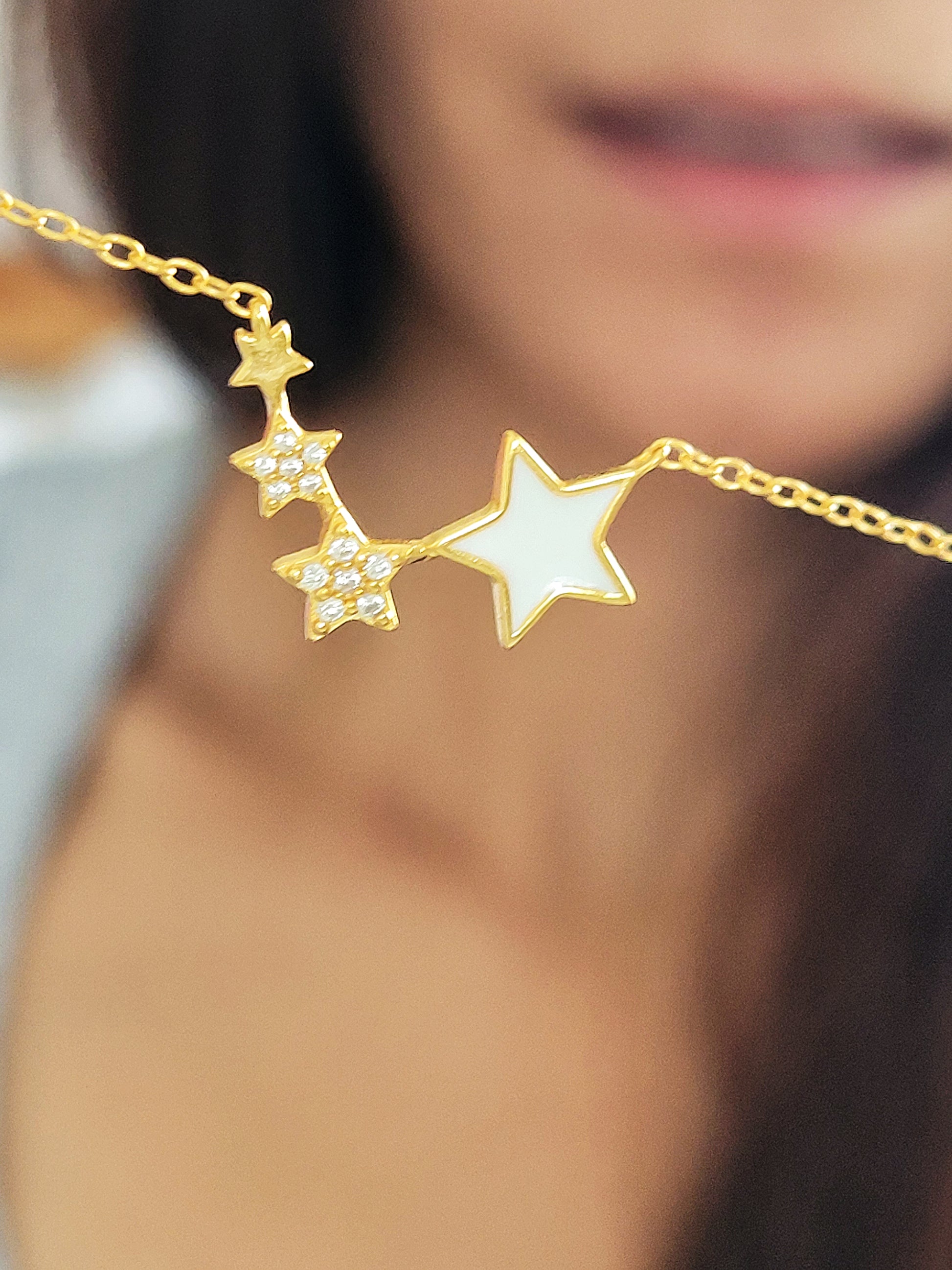 A girl holding a four stars pendant necklace.